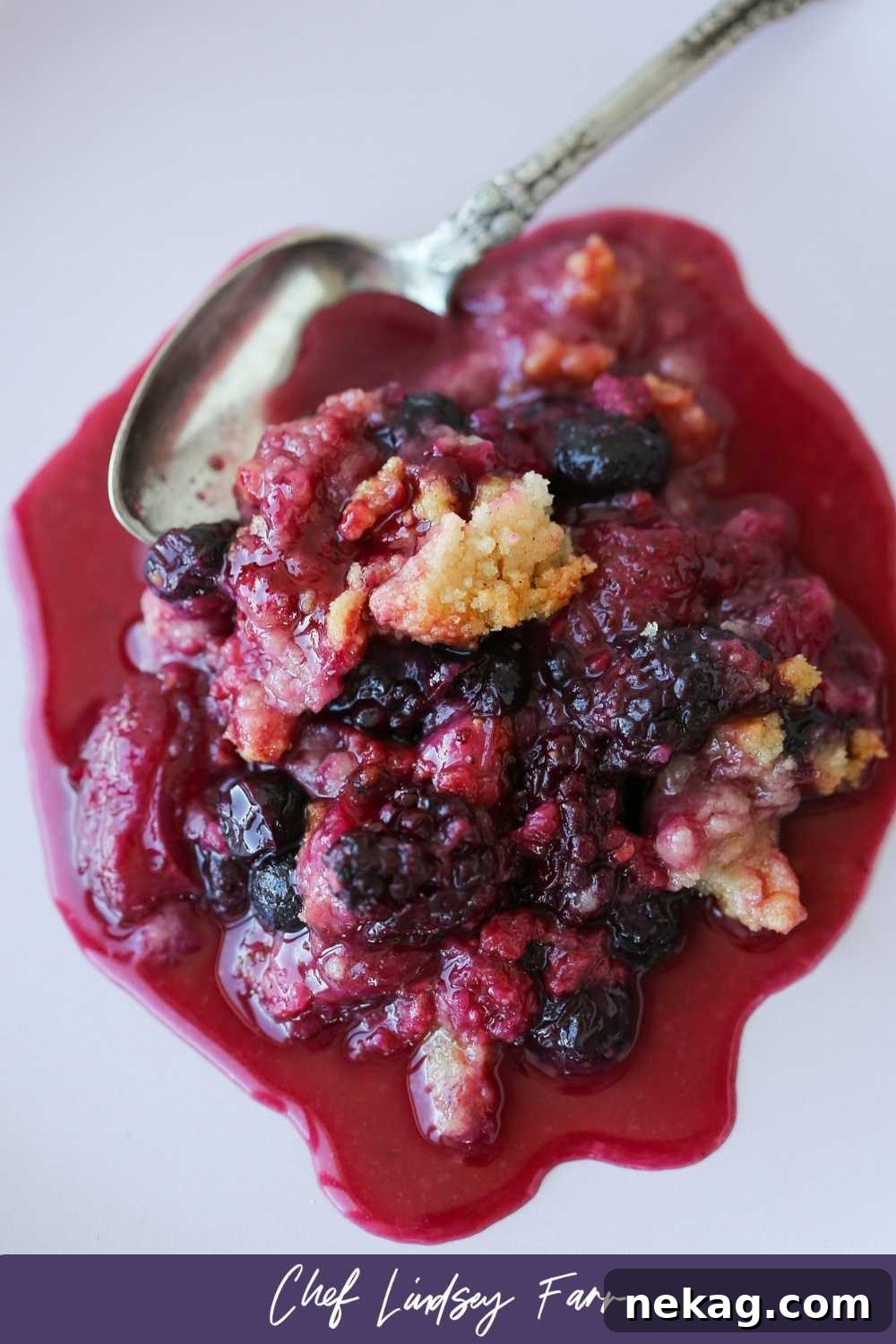 Warm Berry Crumble Bliss 7 A spoonful of mixed berry crumble being lifted from the baking dish, showing the contrast between the golden-brown topping and the warm, juicy berry filling.