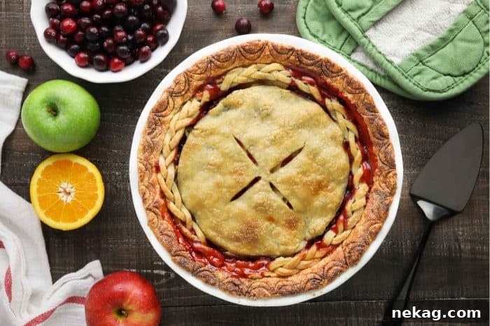 A golden brown, baked Cranberry Apple Pie with a decorative braided crust, cooling on a wire rack.
