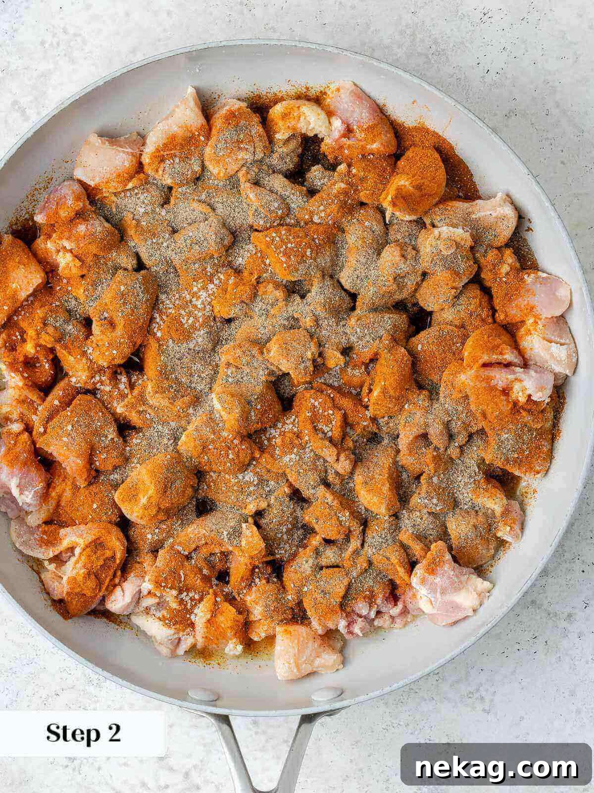 Classic Hungarian Chicken Paprikash 5 Chicken with spices in pan.