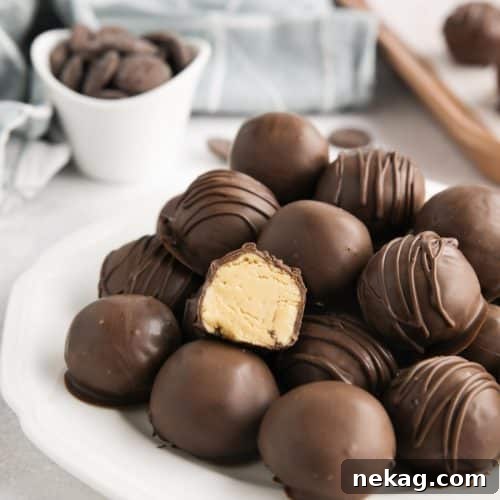 No-Bake Peanut Butter Truffles 12 Easy peanut butter balls stacked on a plate focusing in on one that has been cut in half to show the inside.
