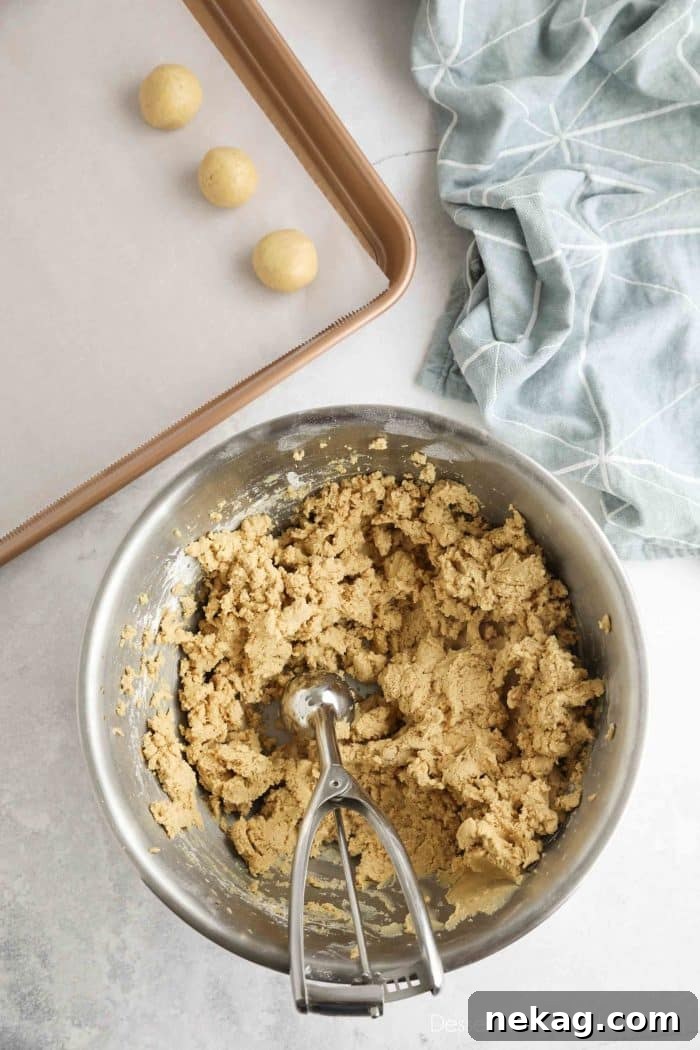 No-Bake Peanut Butter Truffles 6 Peanut butter candy batter being scooped and rounded into balls.