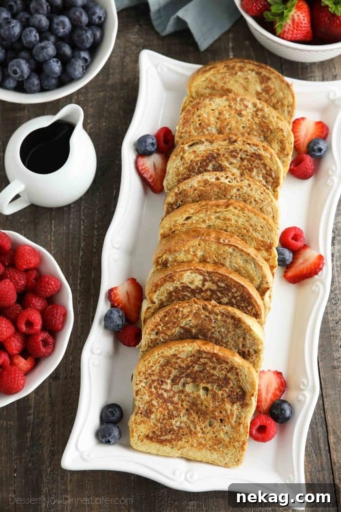 Ultimate Cinnamon French Toast Tutorial 2 Long rectangular plate with golden-brown French toast layered on top, garnished with fresh mixed berries and a drizzle of maple syrup.