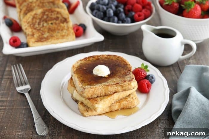 Ultimate Cinnamon French Toast Tutorial 11 A stack of perfectly golden Classic French Toast slices, topped with a melting pat of butter and generously covered in maple syrup.