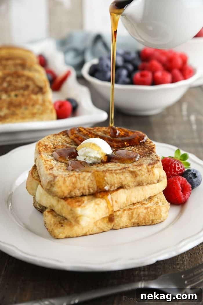 Ultimate Cinnamon French Toast Tutorial 3 Classic French Toast stacked on a plate, being generously drizzled with golden maple syrup.
