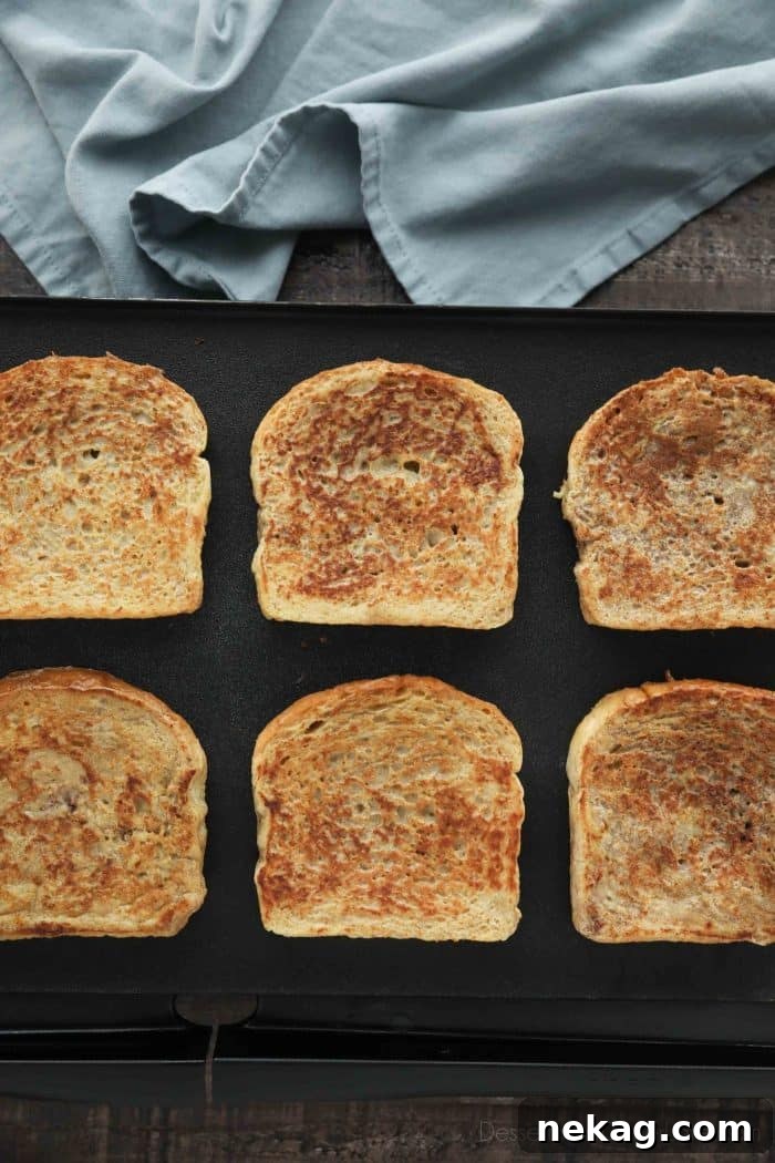 Ultimate Cinnamon French Toast Tutorial 4 Homemade French toast slices cooking to golden perfection on a hot griddle, with steam gently rising.