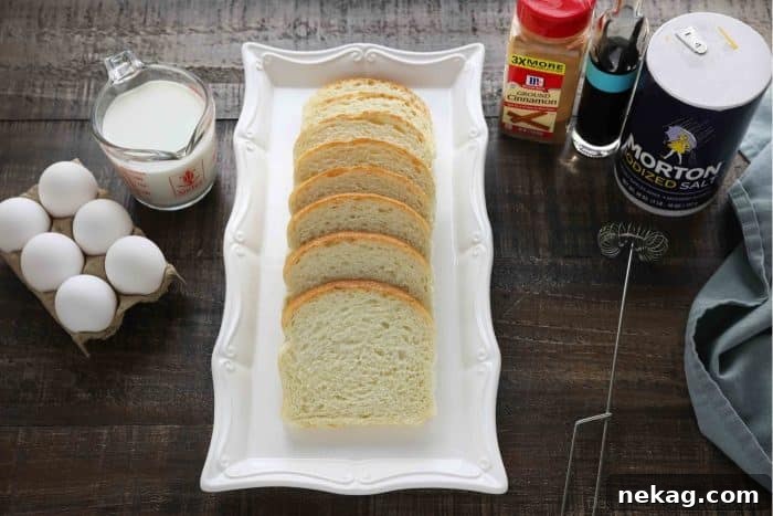 Ultimate Cinnamon French Toast Tutorial 5 French Toast ingredients neatly arranged: fresh eggs, a carton of milk, slices of bread, a bowl of ground cinnamon, a bottle of vanilla extract, and a small pinch of salt.