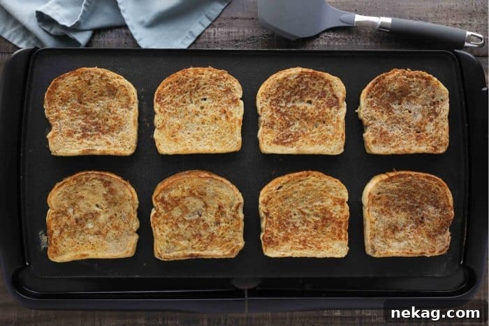 Ultimate Cinnamon French Toast Tutorial 9 Several slices of Classic French toast cooking evenly on a large electric griddle, turning golden brown.