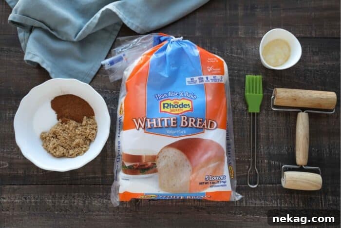 Effortless Cinnamon Swirl Delight 4 Ingredients for cinnamon swirl bread laid out: a package of Rhodes frozen White Bread, a bowl of granulated and brown sugar mixed with cinnamon, a pastry brush, a mini rolling pin, and a small bowl of melted butter.