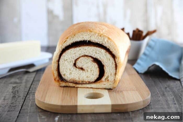 Effortless Cinnamon Swirl Delight 9 A freshly baked loaf of cinnamon bread resting on a cutting board, with a clear view of its beautifully swirled interior.