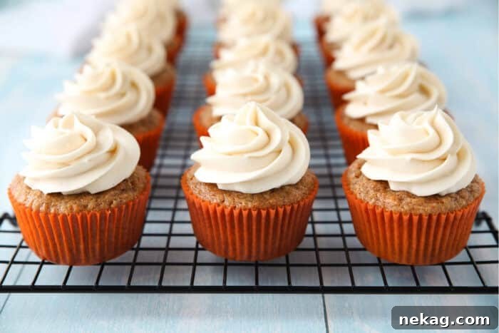 Perfect Carrot Cake Cupcakes 9 Cream cheese frosting piped on top of carrot cake cupcakes on a cooling rack.