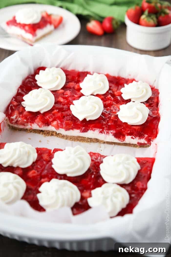 Strawberry Delight Video Recipe 4 A full 13x9-inch baking dish of Strawberry Delight, beautifully cut into squares, each piece artfully topped with a delicate swirl of whipped cream, ready to be served.