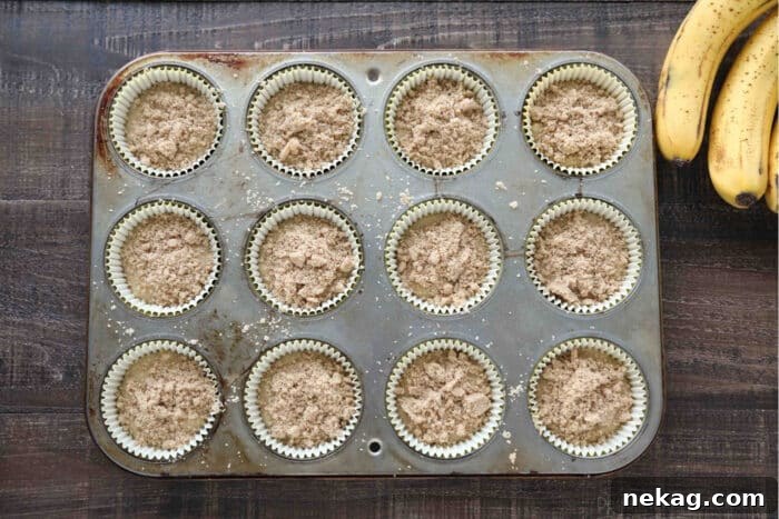 Golden Banana Streusel Muffins 7 Cupcake tin filled with banana muffin batter and cinnamon streusel on top.