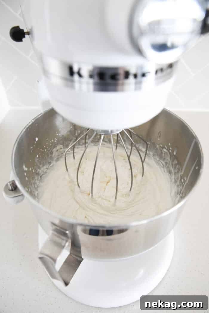 Whipped Cream Cheese Frosting Recipe and Video Tutorial 5 Whipped cream cheese frosting being prepared in a stand mixer, highlighting the ease of making this recipe.