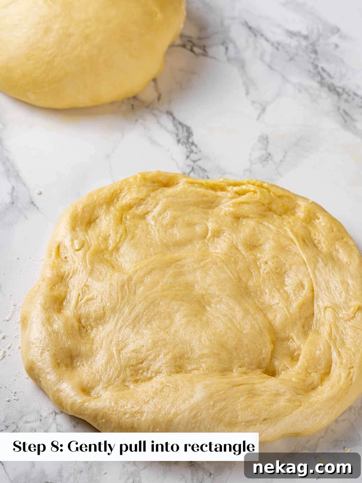 A baker gently pressing brioche dough into a small rectangle on a work surface.