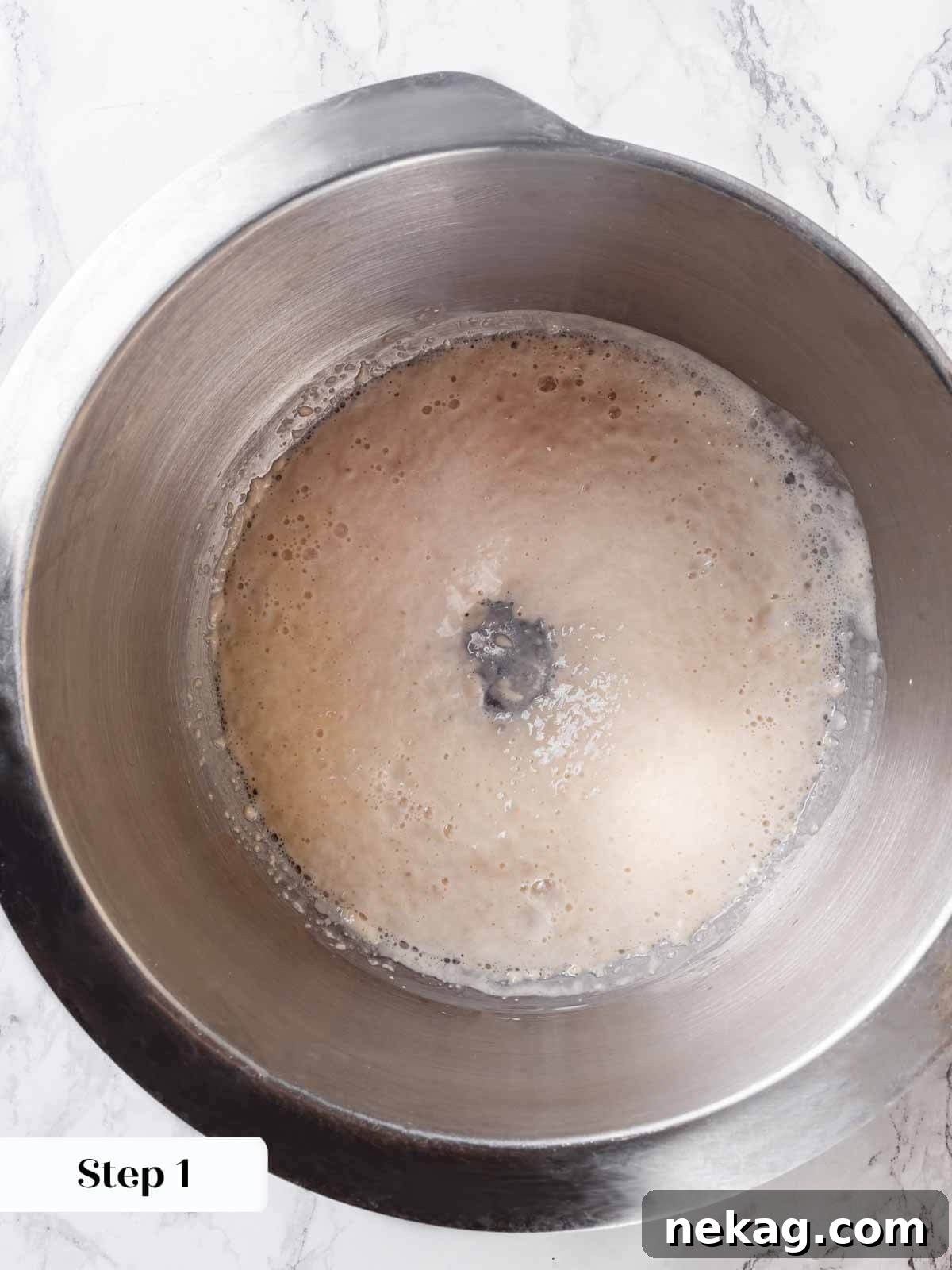 Yeast blooming and bubbling in a stand mixer bowl, ready for brioche bread ingredients.