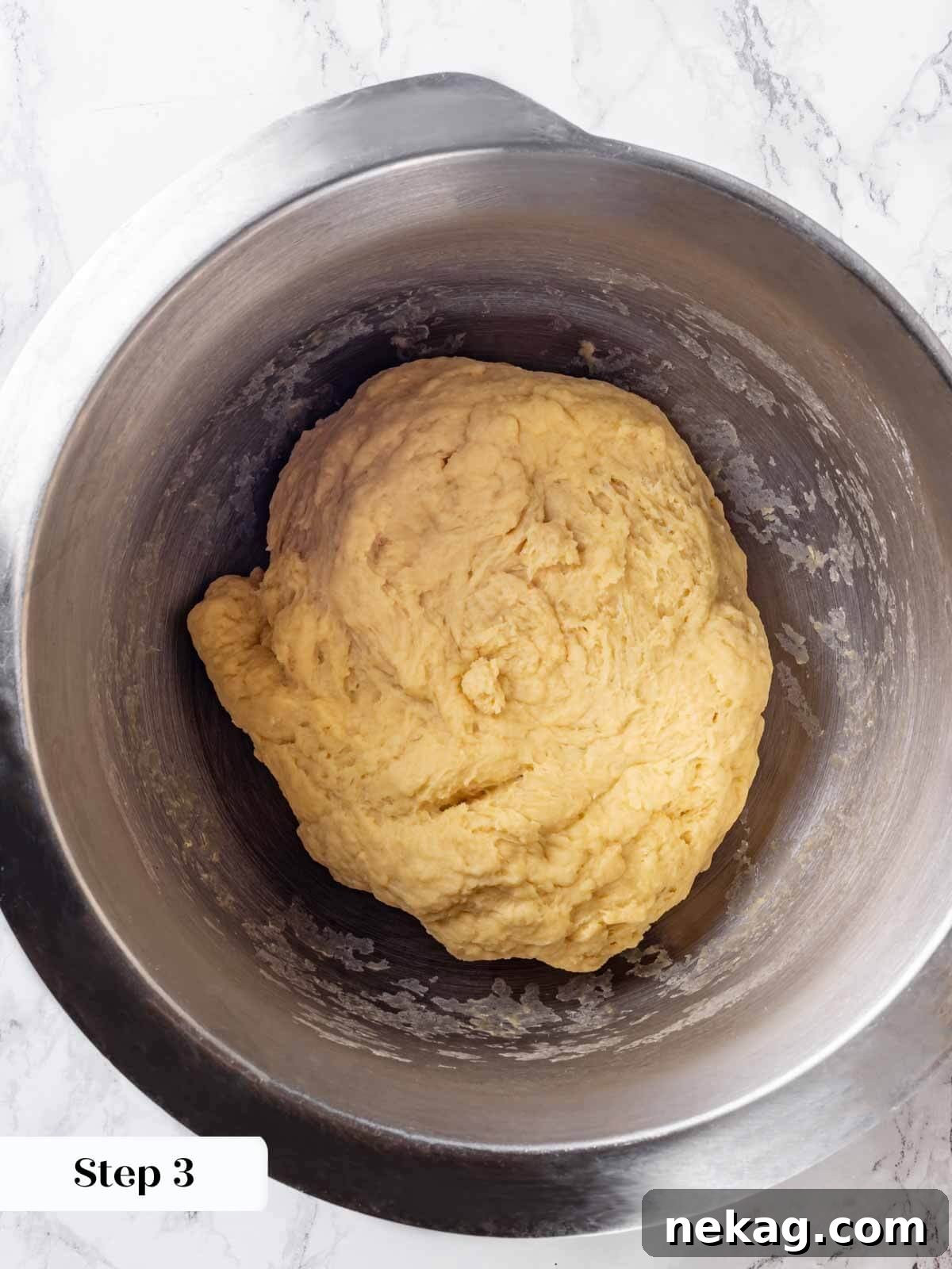 Brioche dough being mixed with the dough hook attachment in a stand mixer, showing good gluten development.