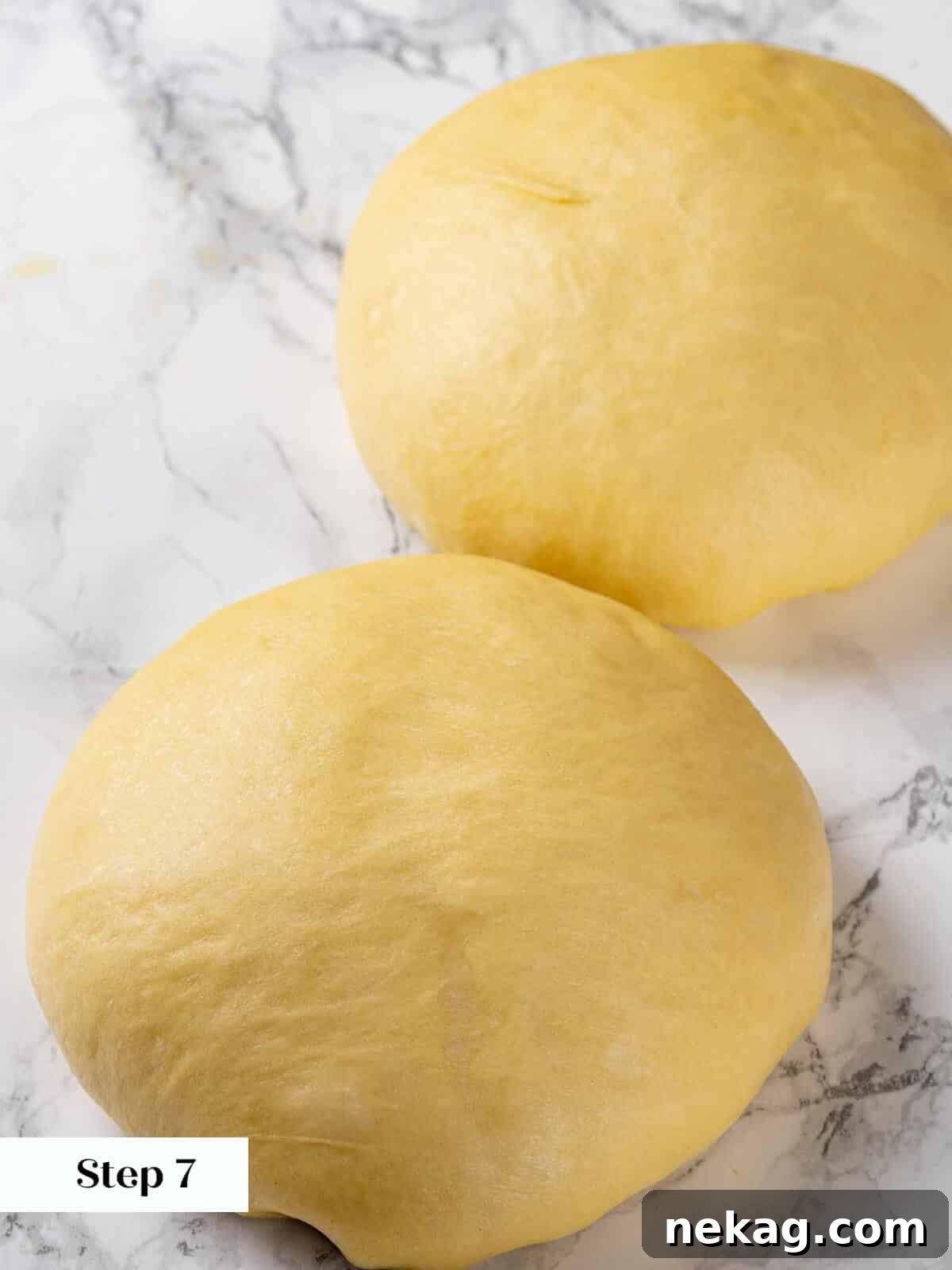 A baker gently pre-shaping a portion of brioche dough into a round on a lightly floured surface.