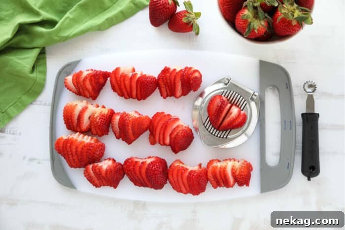 Cutting board full of strawberries that have been sliced with an egg slicer.