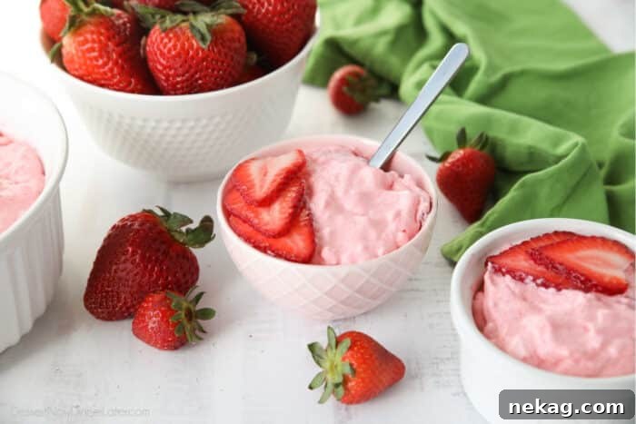 Strawberry Fluff Jello Salad in a bowl with sliced strawberries on top and a spoon inserted into the dessert.