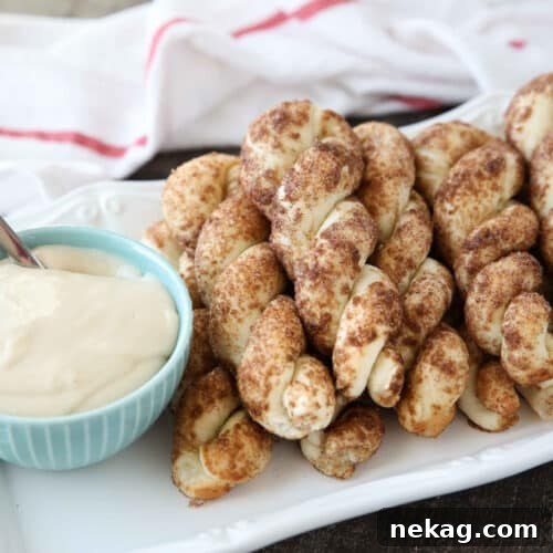 Plate full of cinnamon twists with a bowl of cream cheese dip.