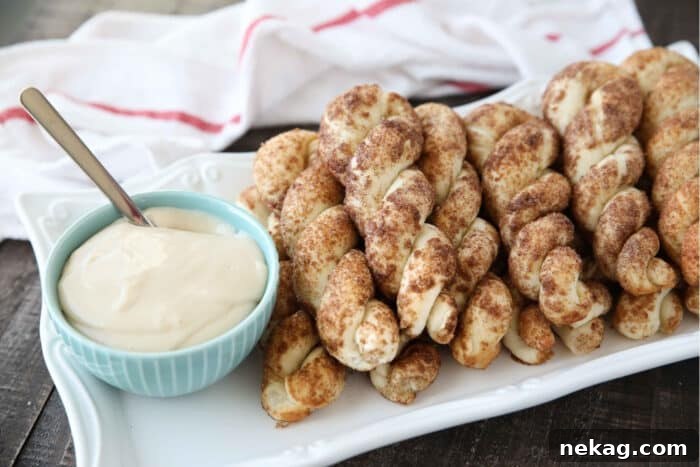 Plate full of cinnamon twists with a bowl of cream cheese dip.