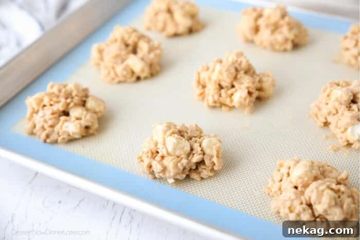 Indulgent Overload Cookies 7 Neat dollops of peanut butter rice krispie treat cookies, resembling Avalanche Cookies, freshly portioned on a sheet tray before chilling.