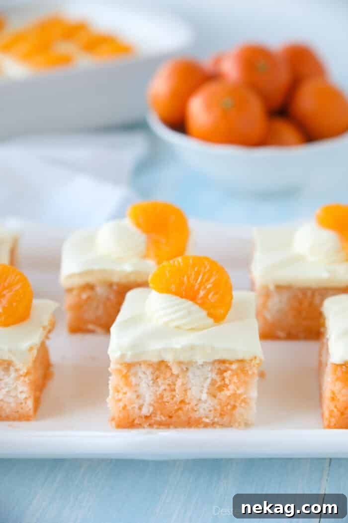 Orange Creamsicle Dream Cake 3 Close up shot of a fluffy slice of orange poke cake, revealing the jello-filled holes and moist texture.