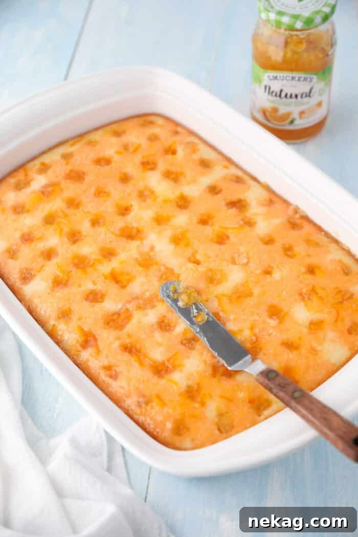 Orange Creamsicle Dream Cake 7 Spreading a thin layer of glossy orange marmalade onto the orange jello-infused cake, adding an extra layer of citrus flavor.