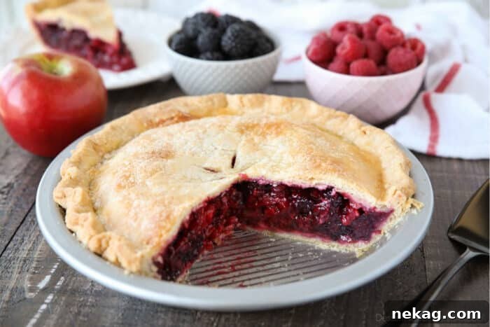 Razzleberry Pie with raspberries and blackberries in a pie tin, with a couple of slices taken out.