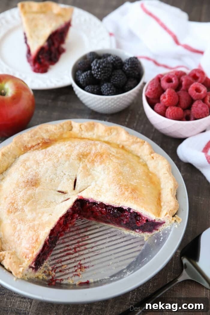 Razzleberry Pie in the pan with a slice on a plate in the background.