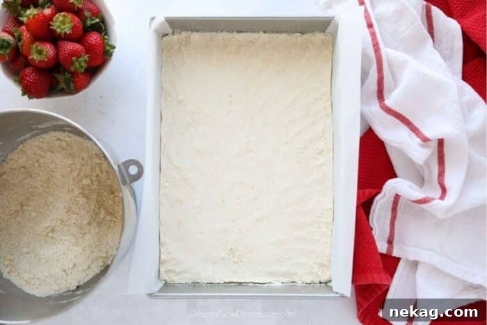 Buttery Strawberry Streusel Bars 6 Half of the crumb streusel mixture pressed flat into a 13x9-inch pan lined with parchment paper, forming the bottom crust.