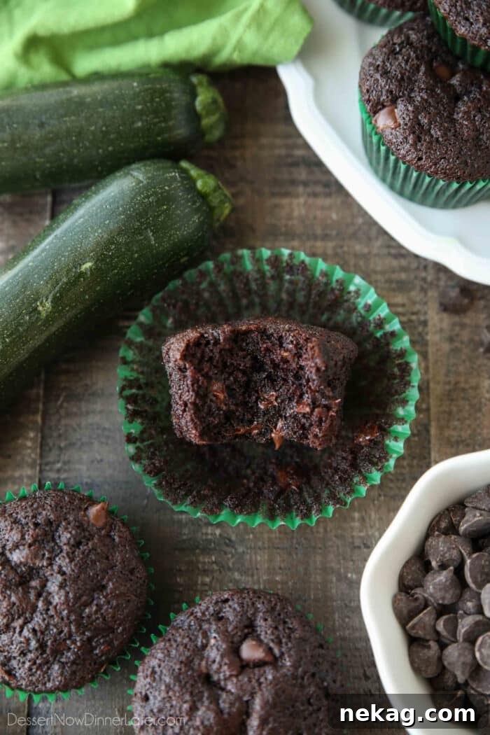 A perfectly baked chocolate zucchini muffin, with a bite taken out, revealing its moist crumb and pockets of melted chocolate chips within.