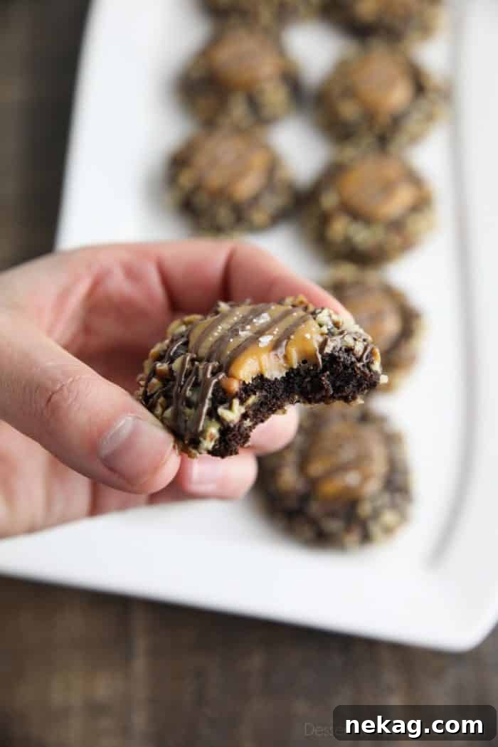 Delicious Turtle Thumbprint Cookies 4 A turtle thumbprint cookie with a bite taken out, revealing the soft chocolate cookie texture and the warm, gooey caramel center, emphasizing its delicious layers.