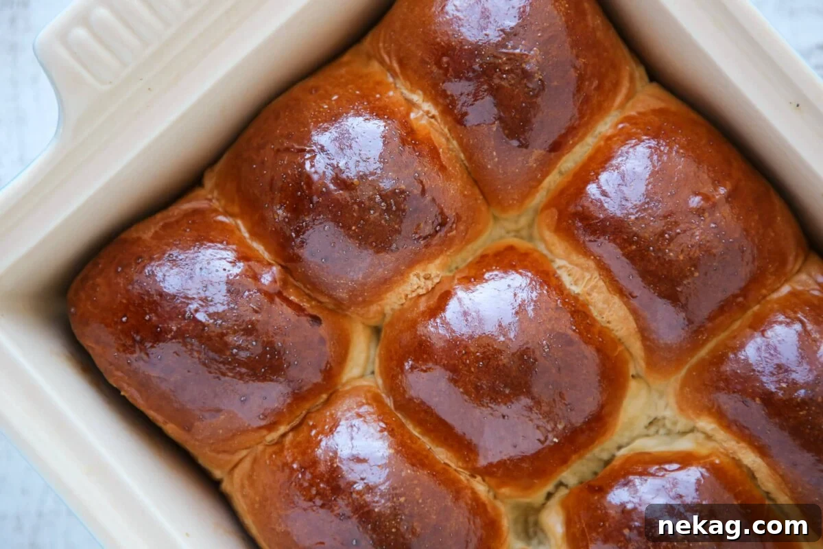 Perfectly Simple Dinner Rolls 3 Four golden-brown dinner rolls on a baking sheet, showcasing their fluffy texture.