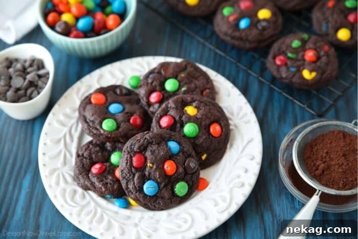 Colorful M and M Chocolate Cookies 5 A white plate generously topped with warm, freshly baked Double Chocolate M&M Cookies, with loose M&M candies scattered around for an appealing display.