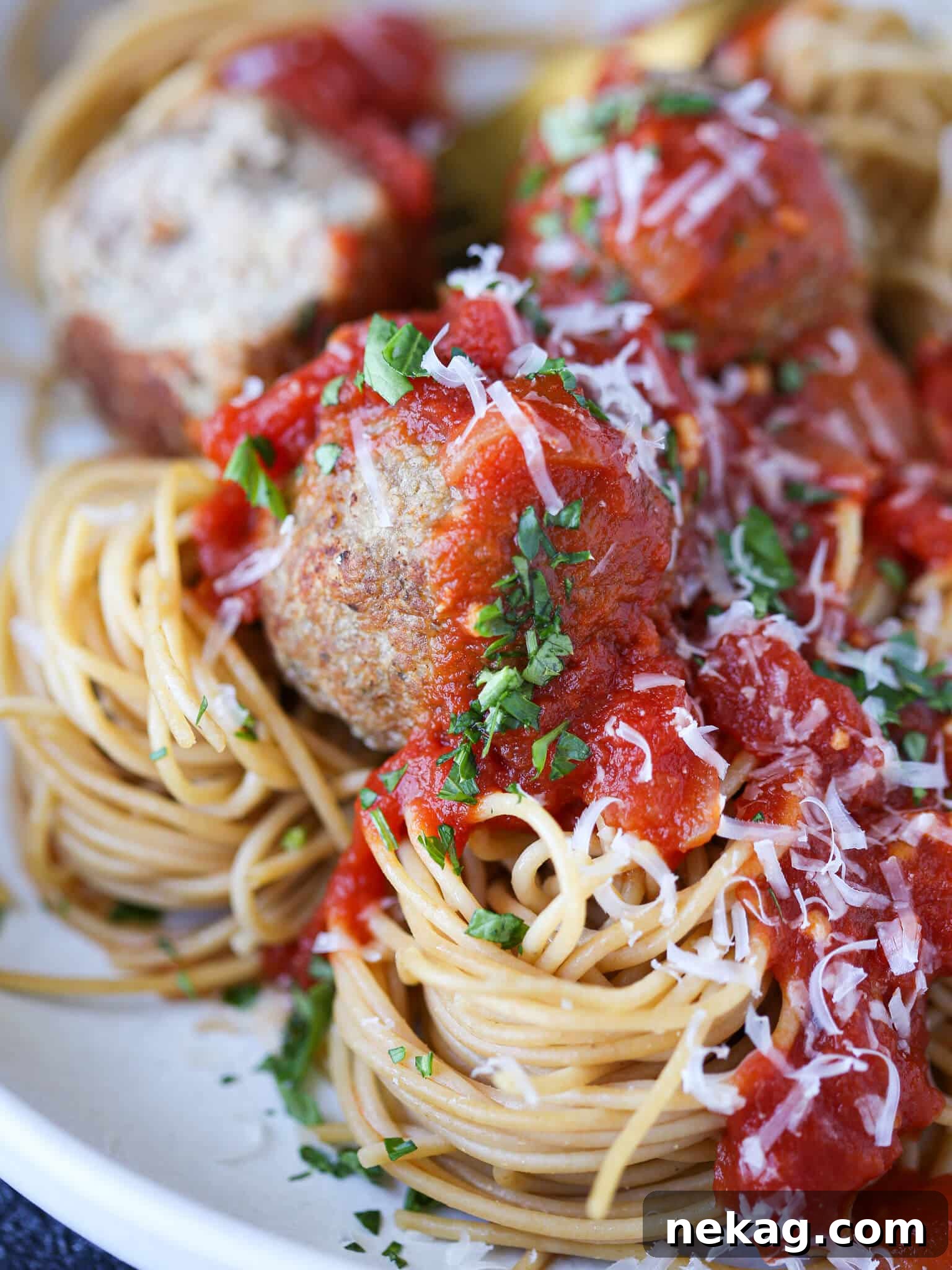 Golden Baked Turkey Meatballs 2 Baked turkey meatballs in a bowl of spaghetti, garnished with fresh basil.