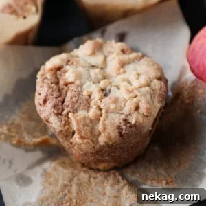 Fresh muffin made with peaches, resting on parchment with golden top and crisp edges.