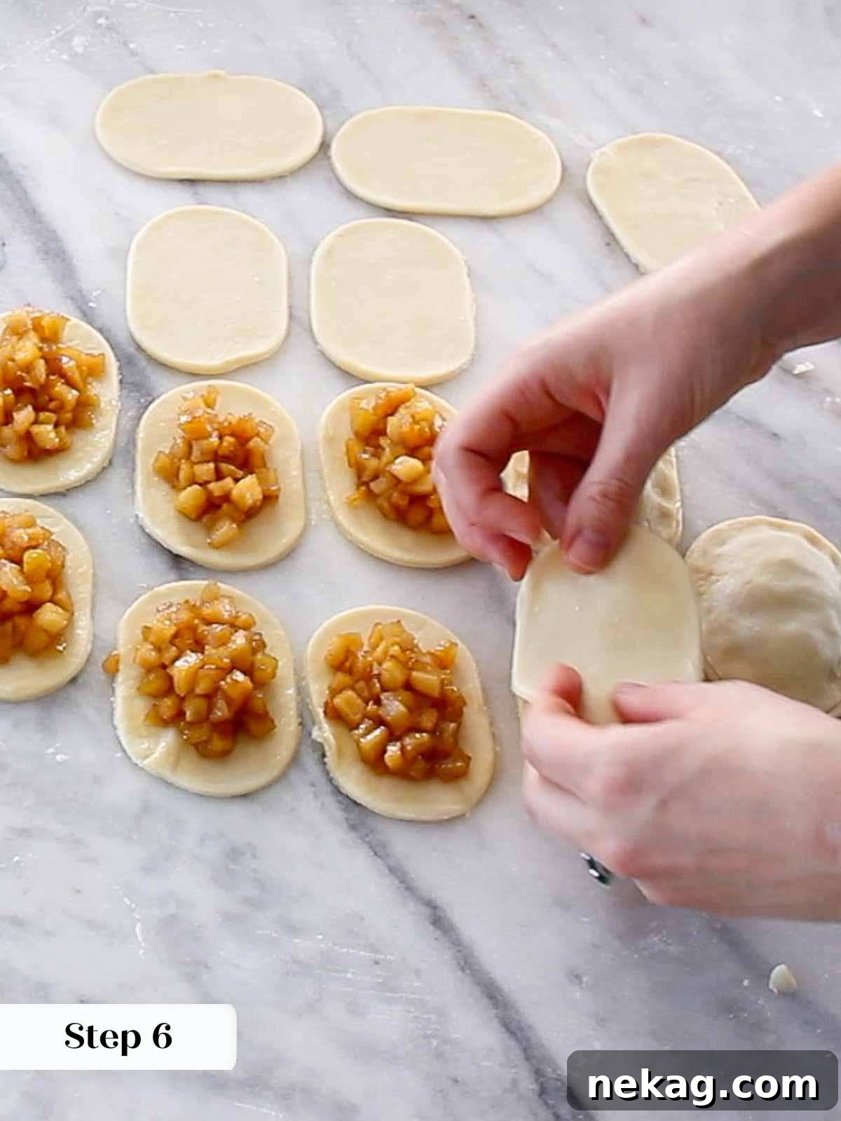 Assembling apple hand pies: apple filling being spooned onto pie dough cutouts on a baking sheet.
