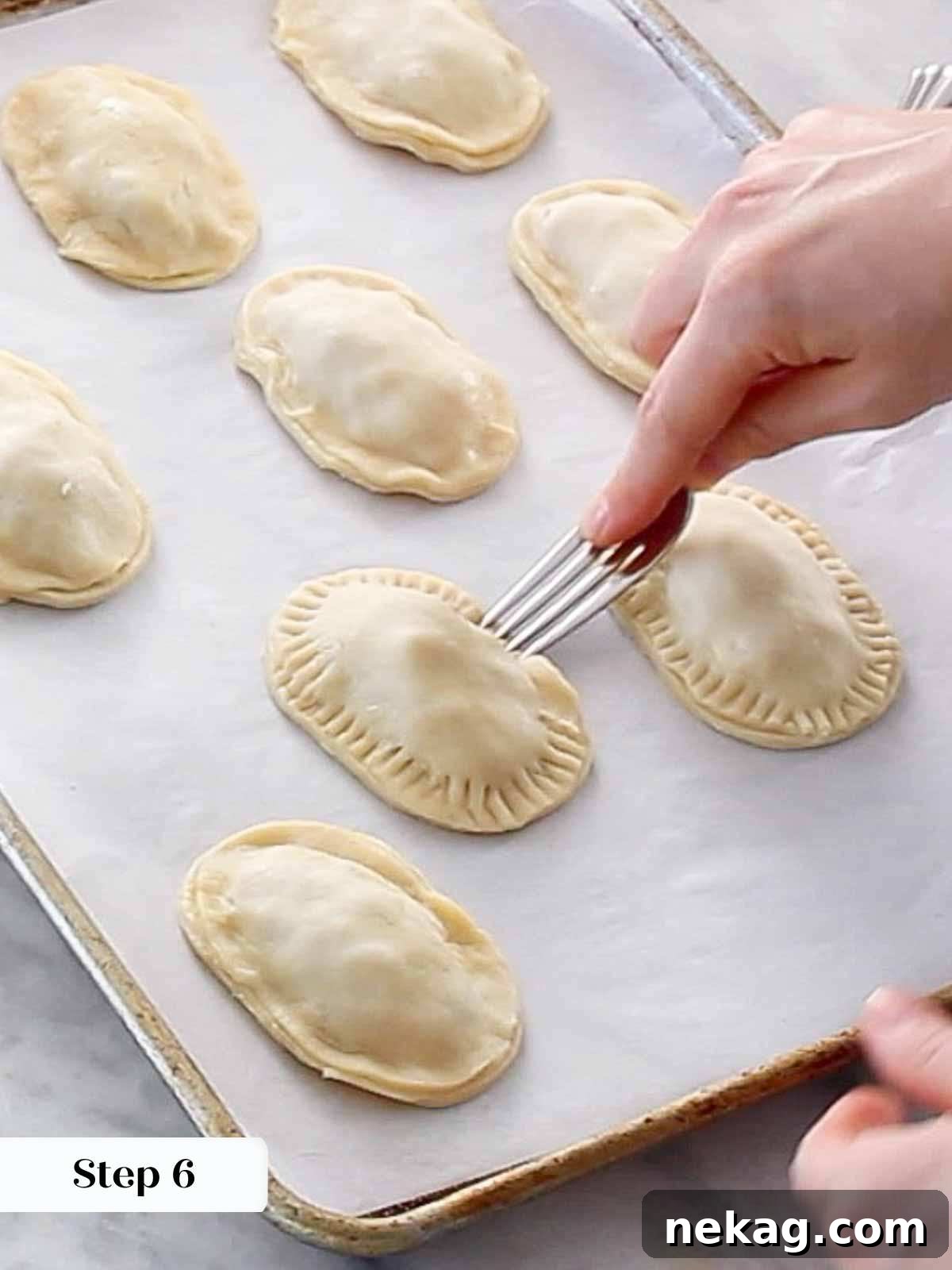 A fork firmly pressing around the edges of an assembled hand pie to create a decorative and secure seal.