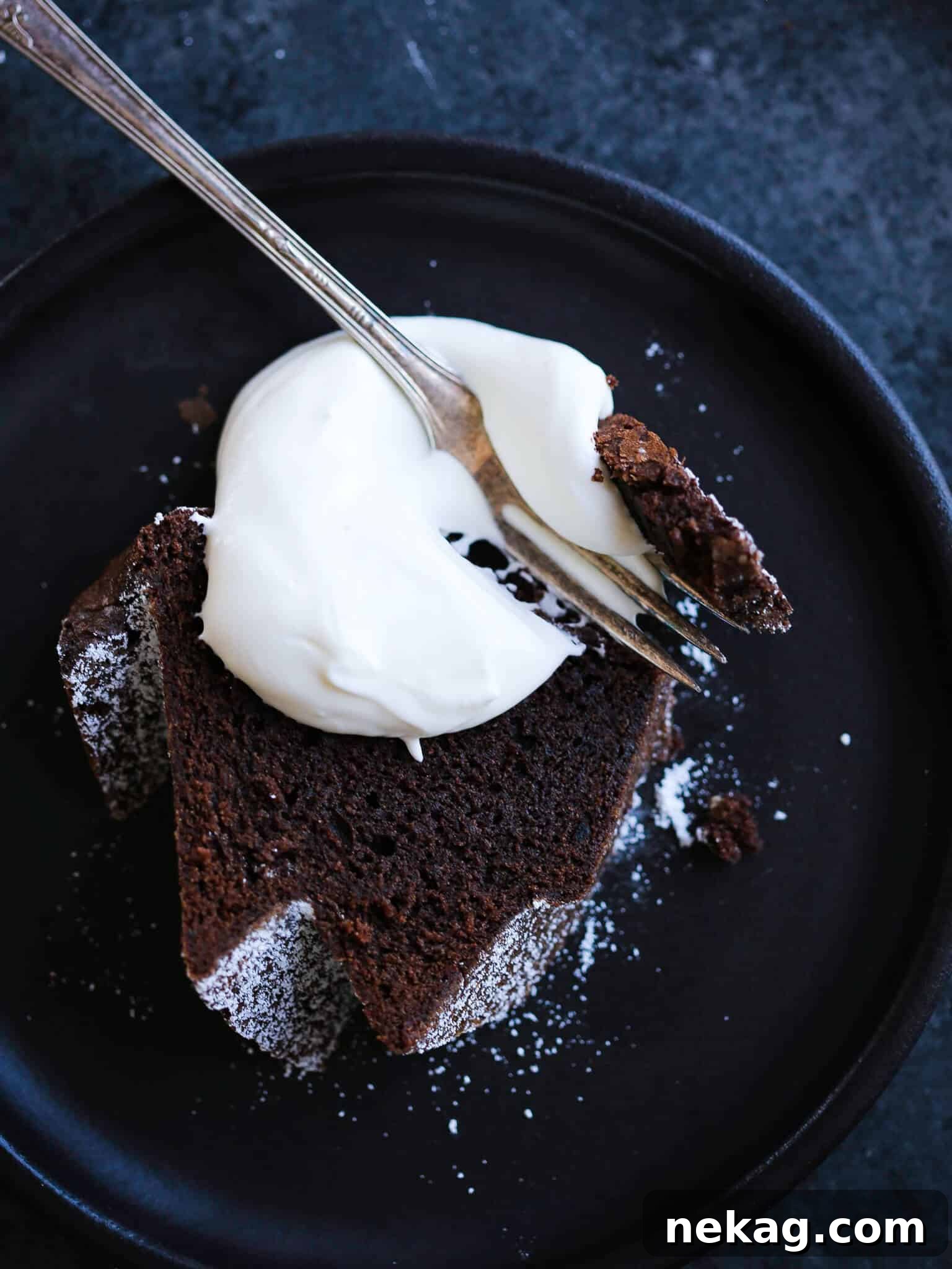 Decadent Chocolate Loaf 2 The best chocolate pound cake sliced with whipped cream on black plate.