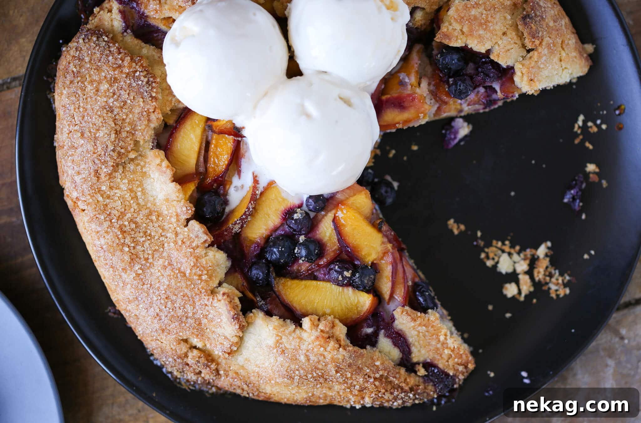 Sun-Kissed Blueberry Nectarine Galette 3 A slice of Blueberry Nectarine Galette topped with a scoop of vanilla ice cream, melting slightly.