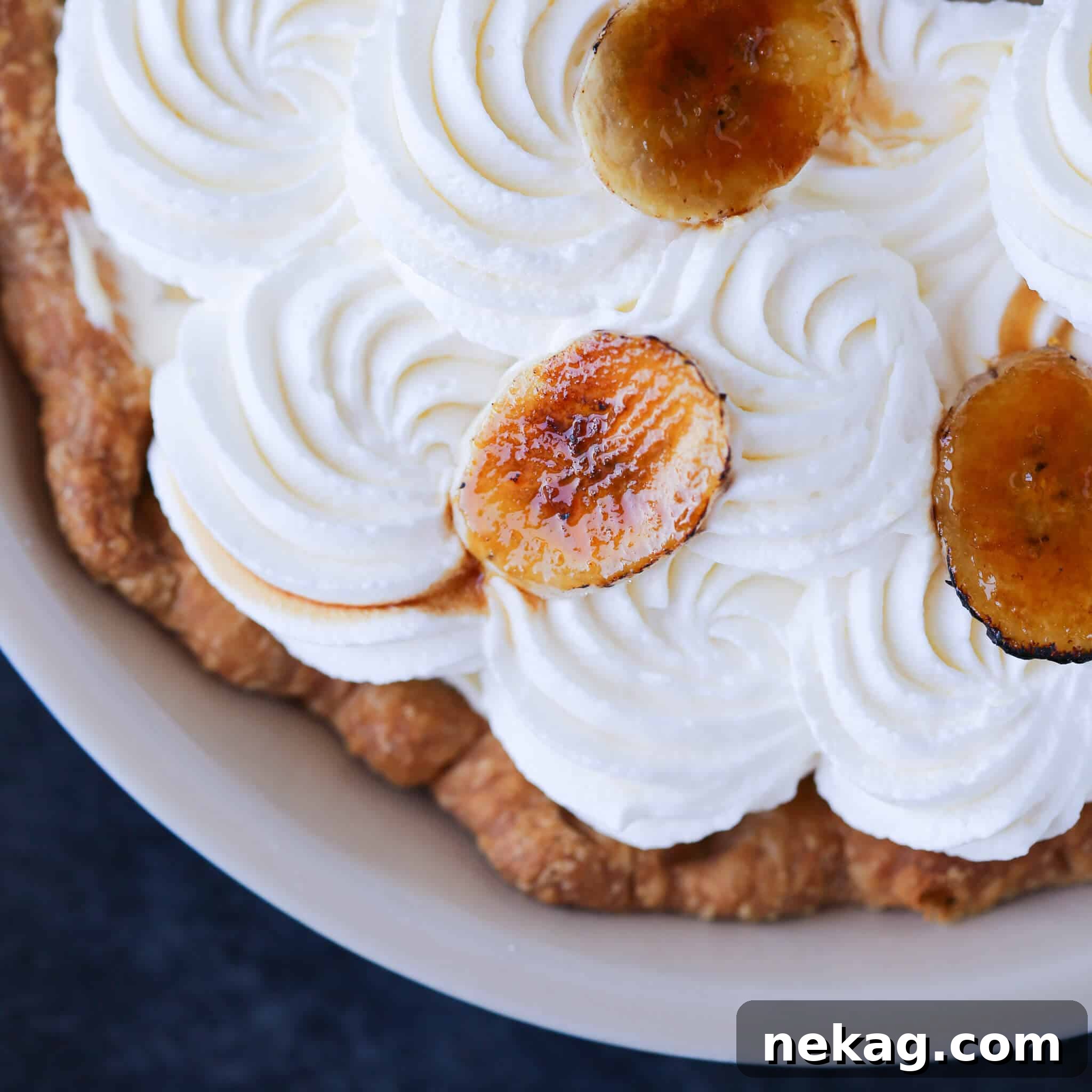 Golden Banana Delight 4 Close-up of Banana Cream Pie with decorative whipped cream swirls on top.