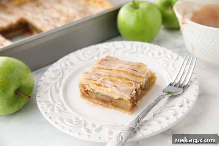 Golden Apple Slab Bake 11 A beautifully glazed slice of apple slab pie presented on a white plate, ready to be enjoyed.