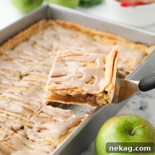 Scooping a piece of Apple Slab Pie out of a 9x13 inch pan.