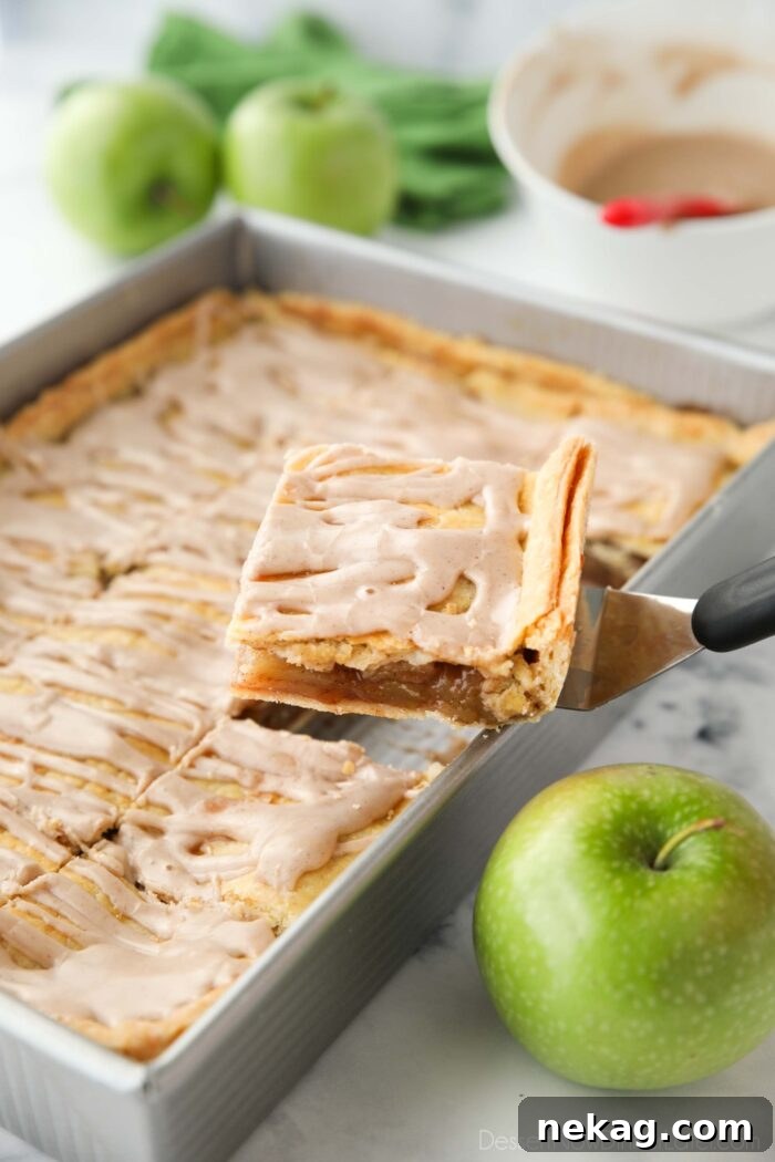 Golden Apple Slab Bake 4 A large serving of apple slab pie being scooped from the 9x13 inch pan, revealing the rich apple filling and golden crust.