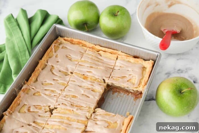Golden Apple Slab Bake 10 A 9x13 inch pan of baked apple slab pie with a single piece removed, highlighting the generous size and inviting appearance.
