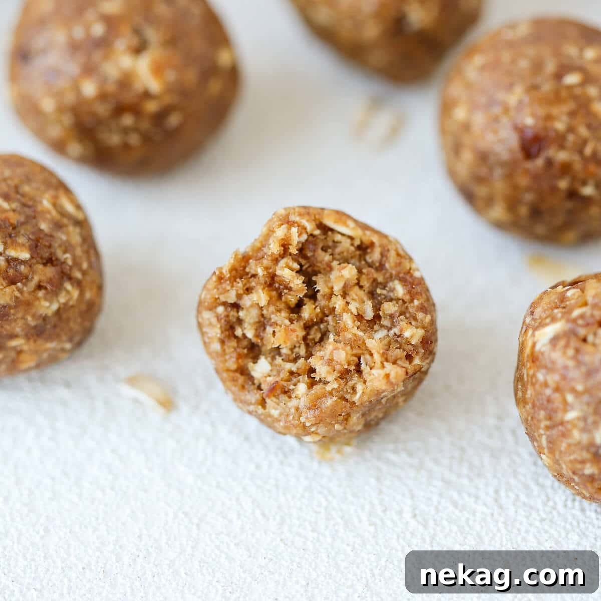 Peanut Butter Banana Fuel Bites 3 A Peanut Butter Banana Energy Bite with a bite taken out, revealing its dense, chewy interior with flecks of oats and dates, showcasing its texture.