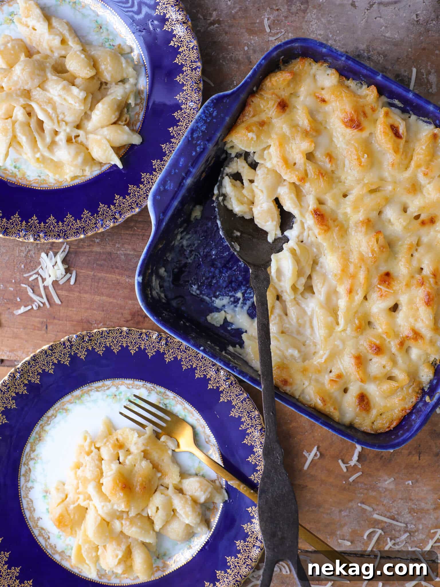 Two plates of perfectly baked white cheddar mac and cheese, served next to a blue baking dish filled with the rest of the creamy dish, ready to be enjoyed.