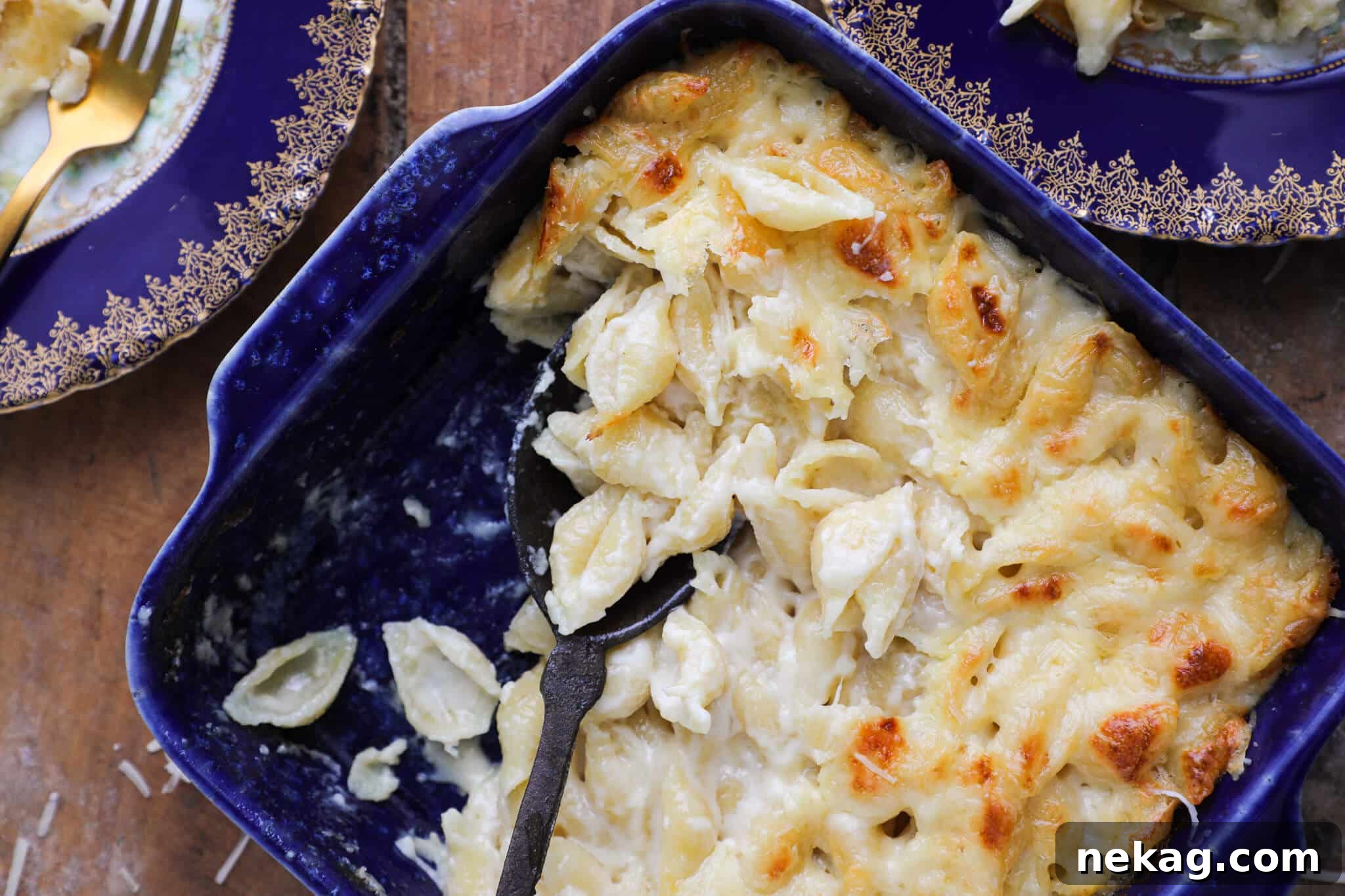 An almost full baking dish of golden-brown white mac and cheese, served on a rustic wood slate counter, ready to be enjoyed.