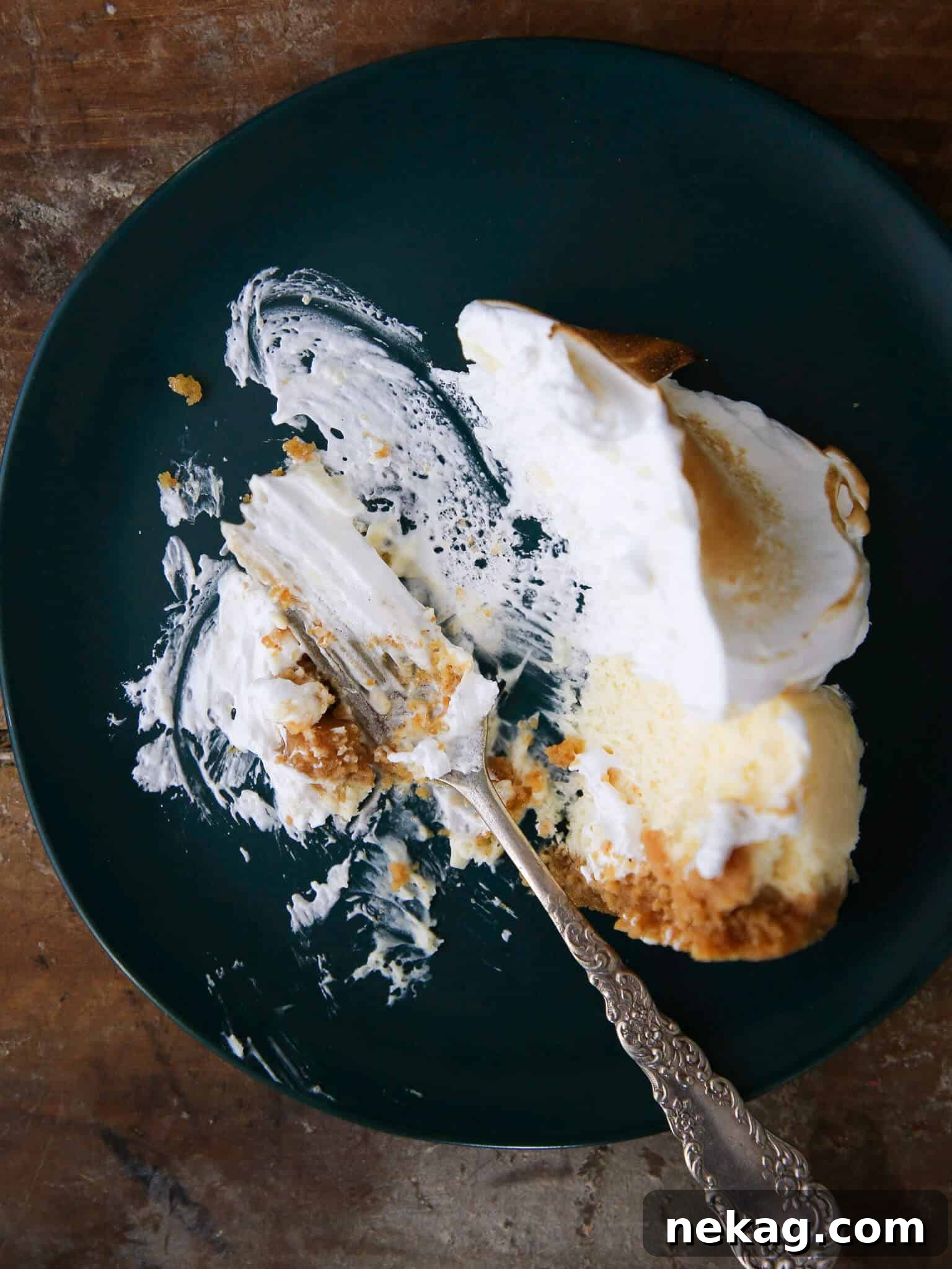 A slice of Lemon Meringue Cheesecake with a generous dollop of meringue, artfully plated.